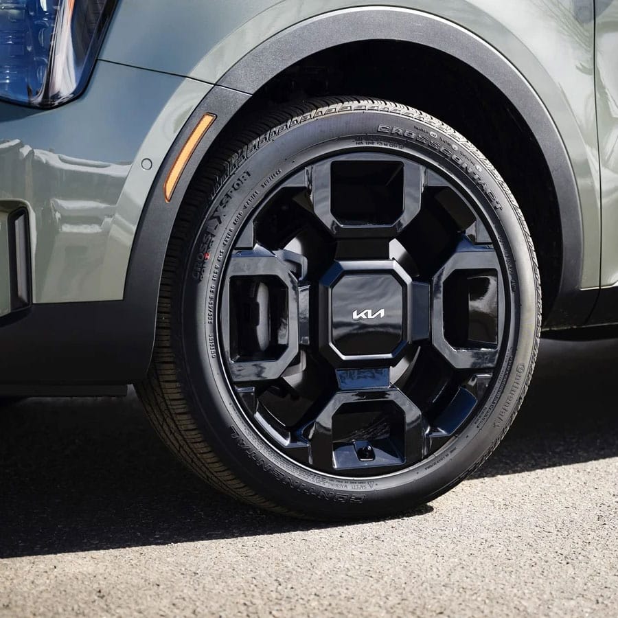 Close-up of a uniquely designed black Kia wheel on a green 2024 Sorento SX-Prestige X-Line.