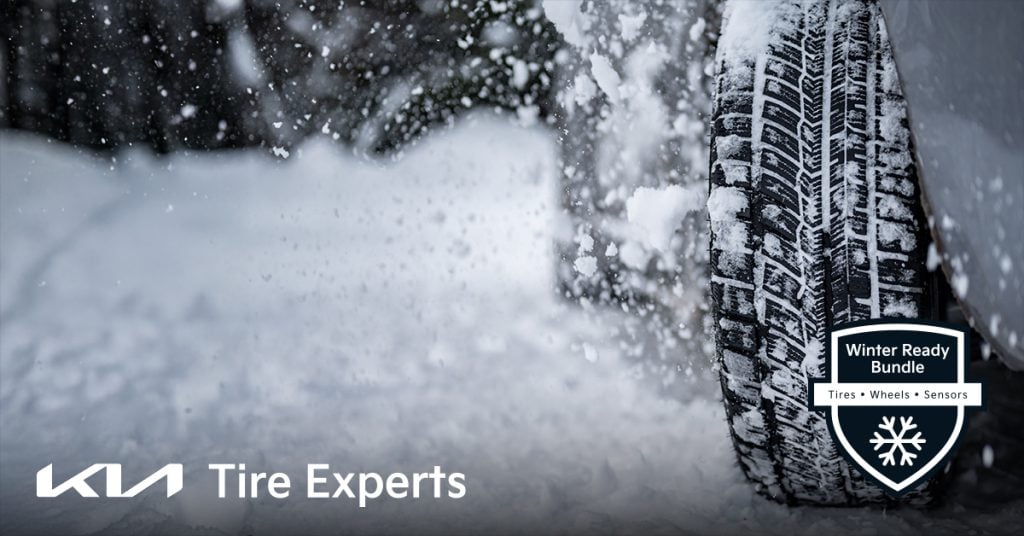 Close-up of a snow-covered winter tire on a vehicle in motion, flinging snow. Badge reads "Winter Ready Bundle – Tires, Wheels, Sensors."